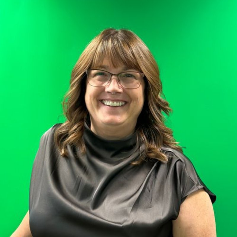 Angie Lederman, audiologist, smiling in glasses and a dark gray satin top